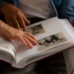 La photo de deux personnes regardant un album de photos, symbolisant l'accompagnement proposé par Une vie des mots pour aider les autres à replonger dans leurs souvenirs