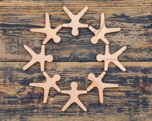 L'illustration de petits personnages en bois, posés à plat sur une table, qui se tiennent la main pour former une ronde