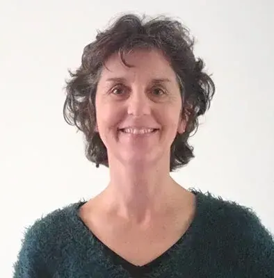 La photo d'une femme souriante, en pull vert sur fond blanc. C'est le portrait de Karine Lamboglia, votre biographe à Nantes (44) pour l'écriture de vos mémoires.