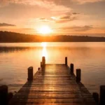 Un ponton en bois s'avançant sur un lac calme au coucher du soleil, symbolisant l'apaisement et le cheminement intérieur d'un récit de vie.
