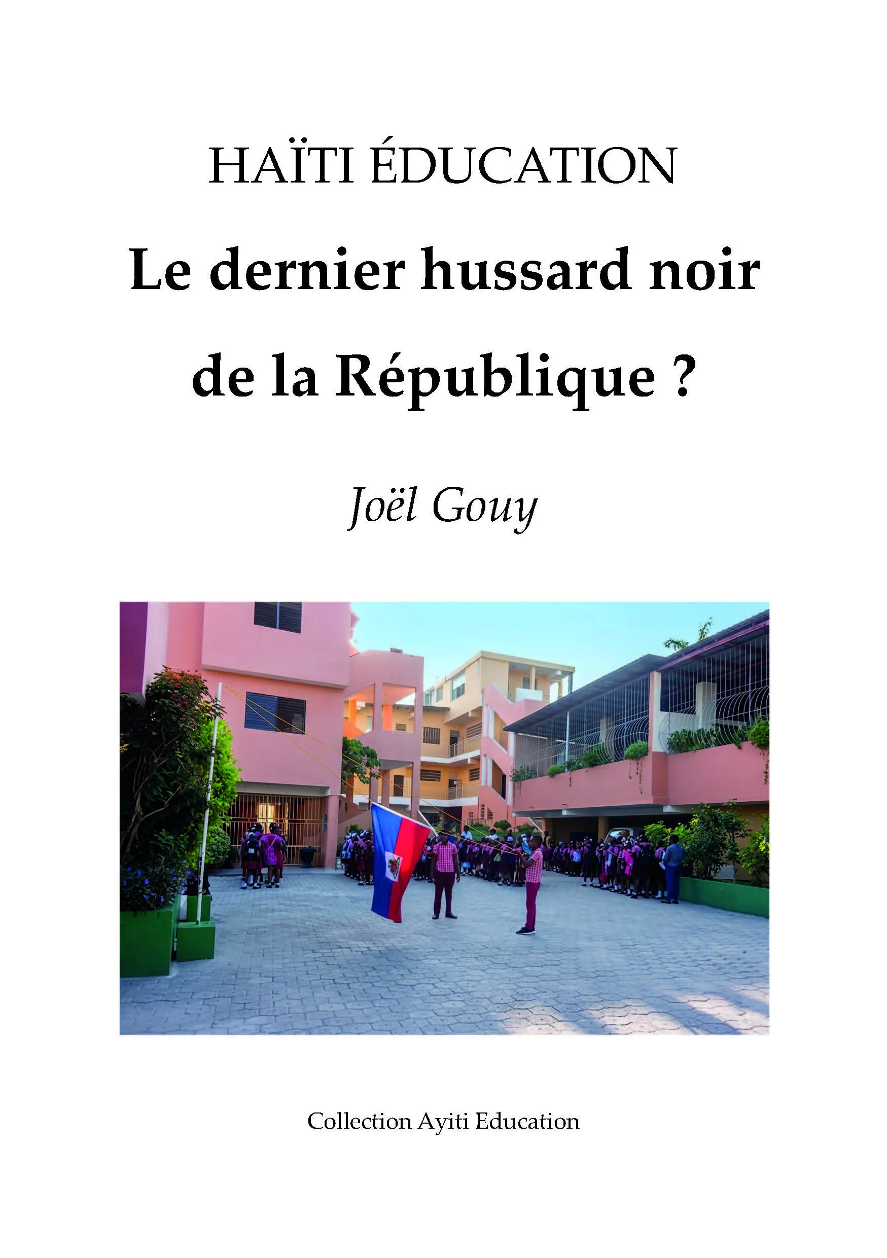 La photo de plusieurs bâtiments de couleur rose et ocre. Des enfants noirs en uniforme scolaire sont réunis dans la cour. L'un deux porte le drapeau haïtien. C'est la couverture du livre "Le dernier hussard noir de la République ?"